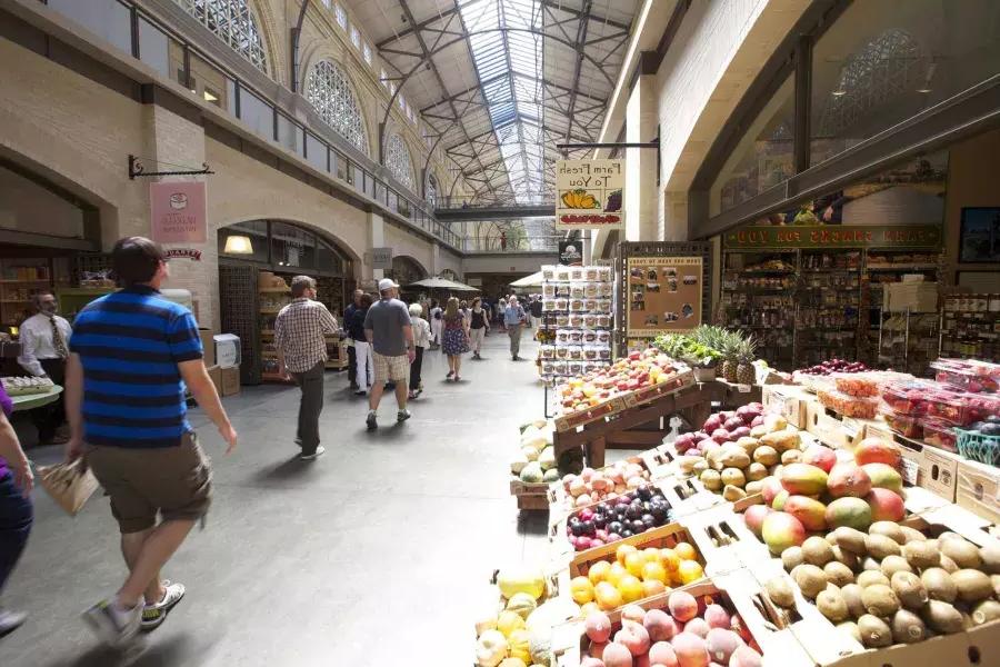 Shoppers walk through the Ferry Building Marketplace, with fresh produce on display.