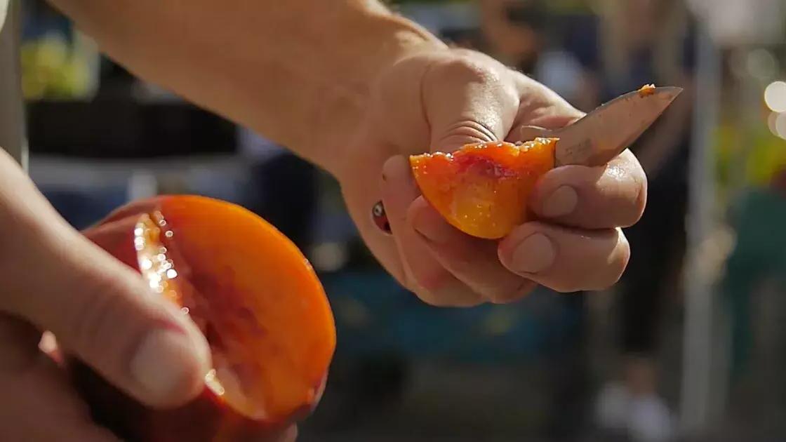 Someone cutting into the fruit at the farmers' market